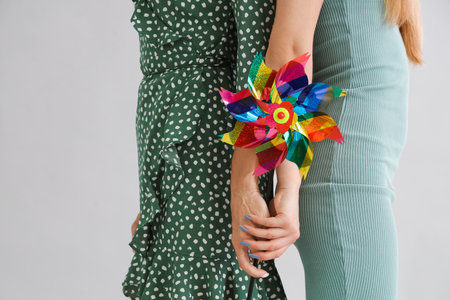Mature woman and her daughter with toy windmill holding hands on light background, closeupの写真素材