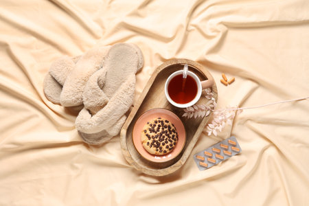 Cup of tea with sweet cookies, pills and slippers on fabric backgroundの写真素材