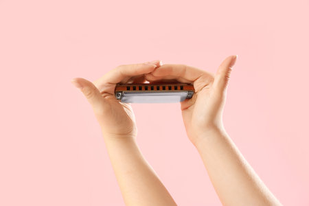 Young woman with harmonica on pink backgroundの写真素材