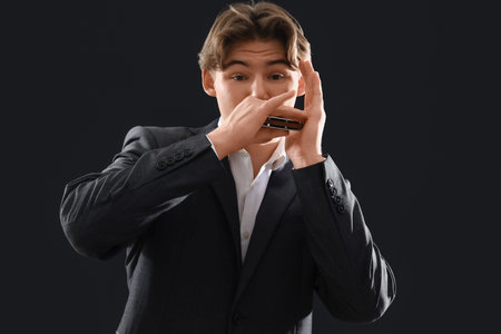 Male artist playing harmonica on dark background