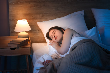 Young pretty woman sleeping on bed in bedroom at nightの写真素材