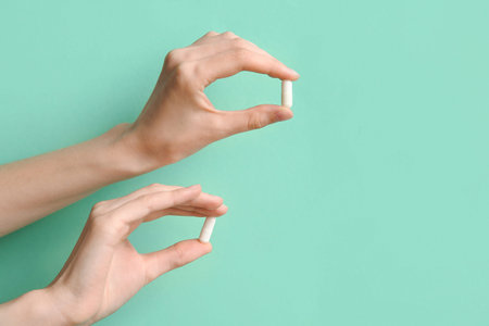 Female hands with pills on turquoise background