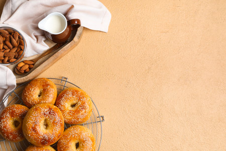 Stand with tasty bagels and bowl of butter on beige background