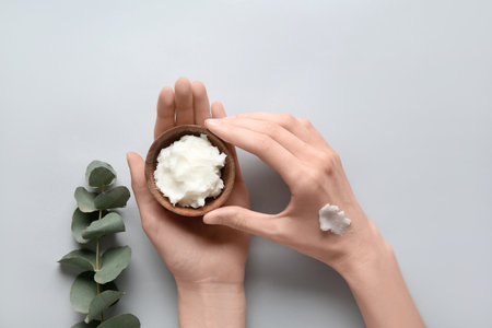 Female hands with bowl of shea butter on white backgroundの写真素材