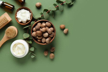 Massage body brushes, nuts, jar and bowl with shea butter on green backgroundの写真素材