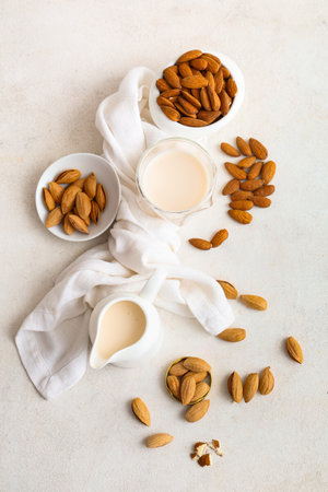 Glass and jug of fresh almond milk with nuts on white backgroundの写真素材
