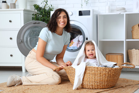 Young mother and her cute little baby in laundry basketの写真素材