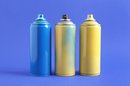 Spray paint cans on blue backgroundの写真素材