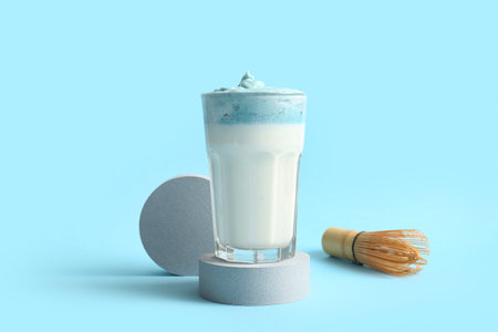 Glass of blue dalgona matcha latte, plaster stands and chasen on blue backgroundの写真素材
