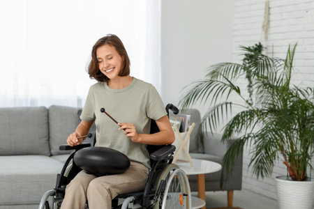 Young pretty woman in wheelchair playing on glucophone at home
