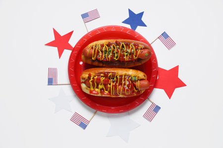 Tasty hot dogs with USA flags and stars on white background. American Independence Day celebrationの写真素材