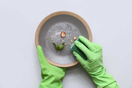 Hands washing dishes on light backgroundの写真素材