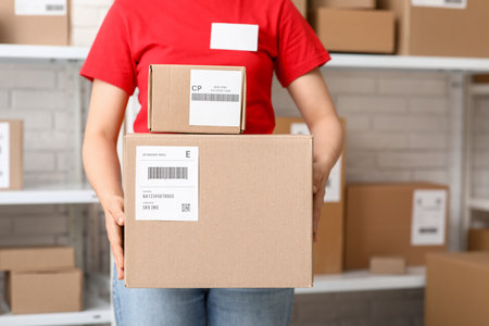 Female worker with parcel boxes at postal warehouse, closeupの写真素材