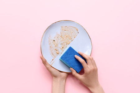 Hands washing dishes on pink backgroundの写真素材