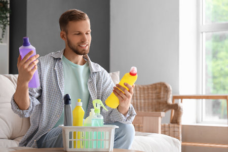 Male janitor and basket of cleaning supplies on coffee table in roomの写真素材
