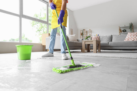Male janitor cleaning floor with mop in light roomの写真素材