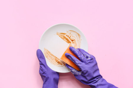 Hands washing dishes on pink backgroundの写真素材