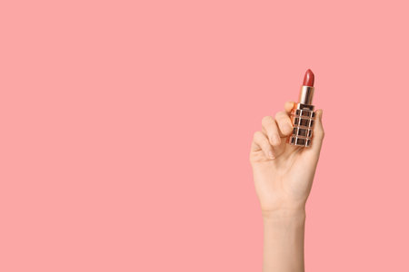 Female hand with lipstick on pink backgroundの写真素材