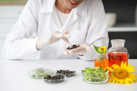 Happy female scientist with flasks of samples, sunflower seeds and sprouts working in laboratory,...