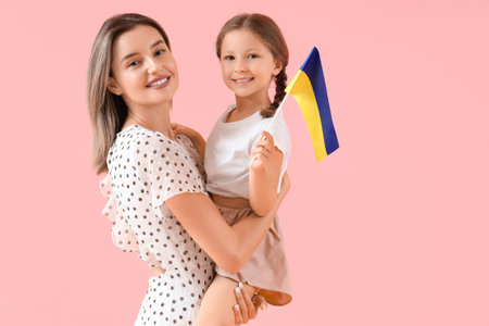 Cute little girl and her mother with Ukrainian flag on pink backgroundの写真素材