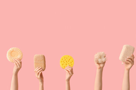 Female hands with different bath sponges on pink background