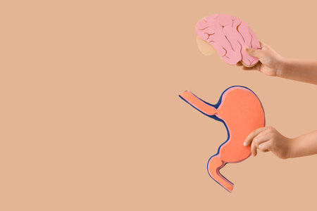 Little boy with paper brain and stomach on beige background