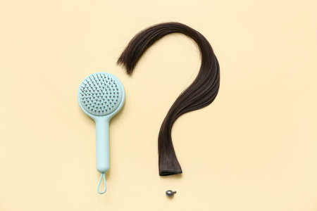 Brush and question mark made of hair strand on beige background