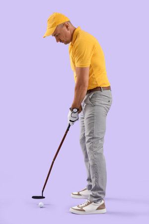 Mature man playing golf on lilac backgroundの写真素材