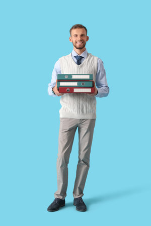 Young businessman with stack of folders on blue backgroundの写真素材