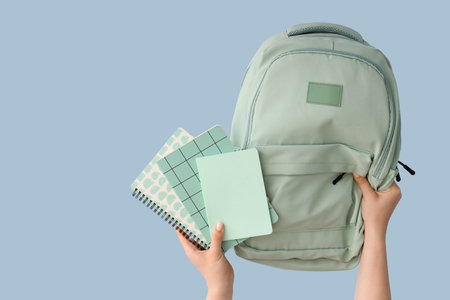 Female hands with notebooks and backpack on blue background
