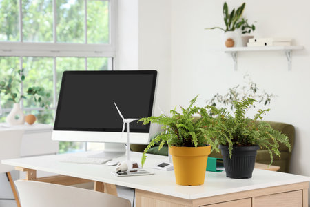 Engineer's workplace with computer monitor, plants and wind turbine model in officeの写真素材