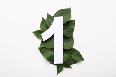Green leaves with paper number one on white background. Top view