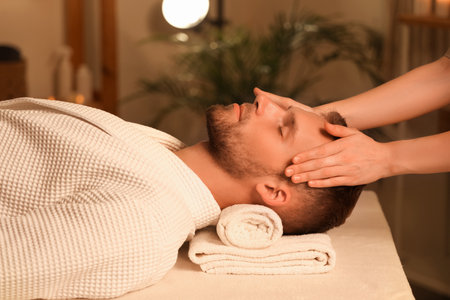 Handsome young man receiving facial massage in beauty salonの写真素材