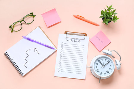 Sticky note with text GOALS, todo list, notebook and alarm clock on pink background