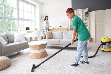 Little African-American boy with his mother cleaning at homeの写真素材