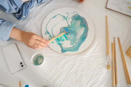 Young woman creating fluid art painting in workshop, top viewの写真素材