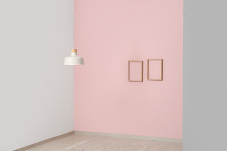 Hanging lamp and frames near pink wall in empty roomの写真素材