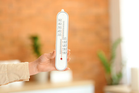 Woman with home thermometer in room, closeup