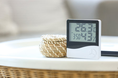 Digital hygrometer with basket and laptop on table in living room, closeupの写真素材