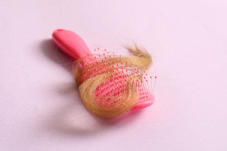 Brush with hair strand on lilac background. Hair loss problemの写真素材