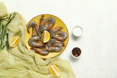 Plate with fresh raw shrimps, lemon and rosemary on white backgroundの写真素材