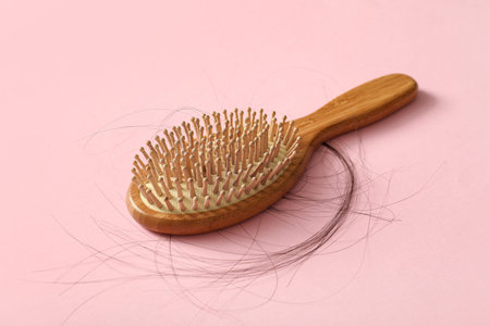 Brush with hair strand on pink background. Hair loss problemの写真素材