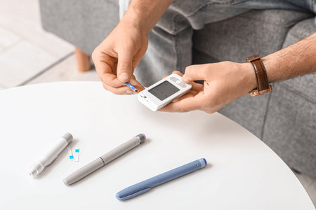 Diabetic young man using glucometer at home, closeup