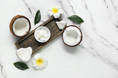 Wooden tray, flowers and bowl with natural coconut oil on marble background