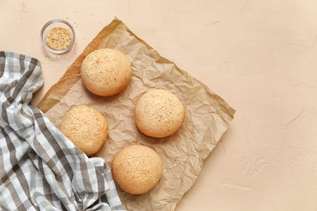 Baking paper of fresh buns with sesame seeds on beige background