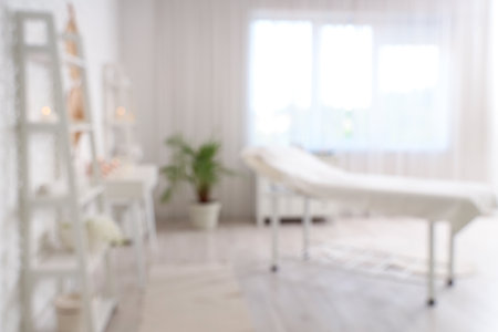 Blurred view of light spa salon with couch, candles and white furnitureの写真素材
