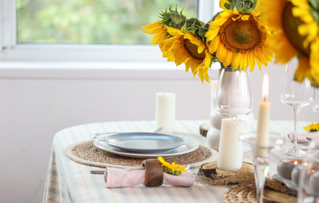 Table setting with burning candles and sunflowers in dining roomの写真素材