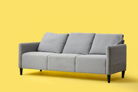 Comfortable gray sofa on yellow backgroundの写真素材
