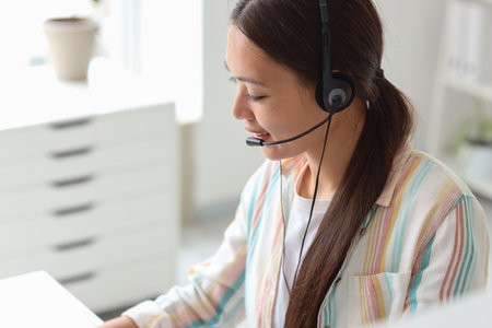 Young female receptionist in headset working in officeの写真素材