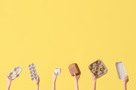 Female hands holding paper garbage on yellow background. Recycling conceptの写真素材